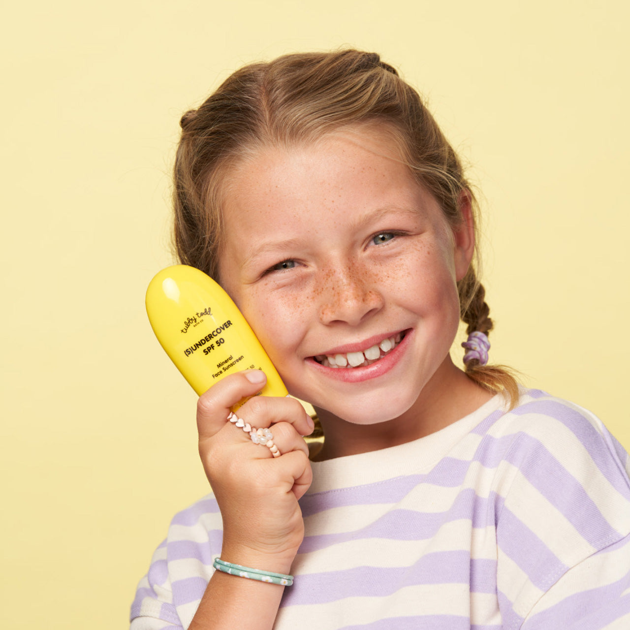 Child holding (S)undercover bottle next to face smiling